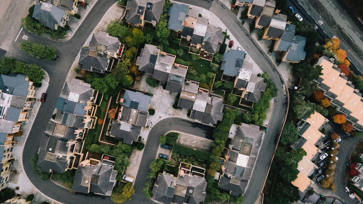 Aerial view of suburban houses and trees along a curving street