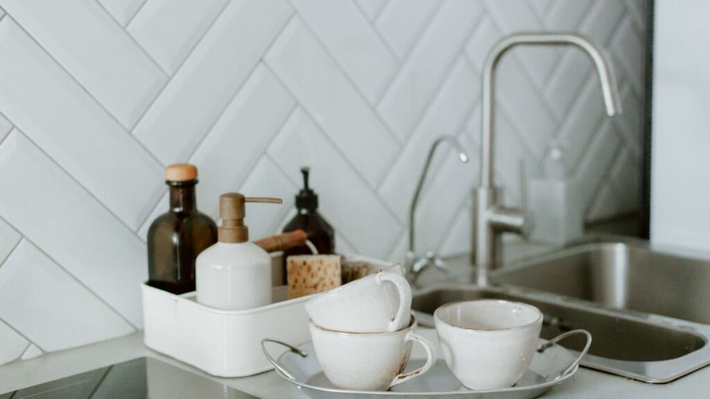 White kitchen sink with a chrome tap and cups on the counter