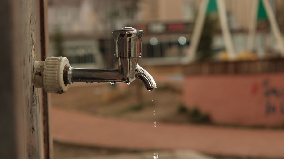 Close-up of a chrome outdoor faucet with a drop of water at the spout