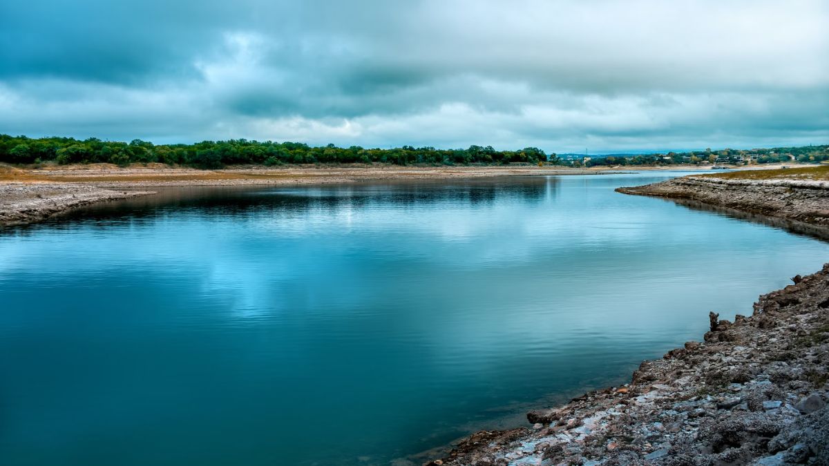 Wide river with low rocky banks reflecting a cloudy sky