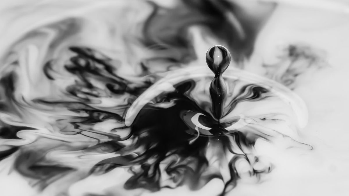 Black and white close-up of a water drop falling into still water