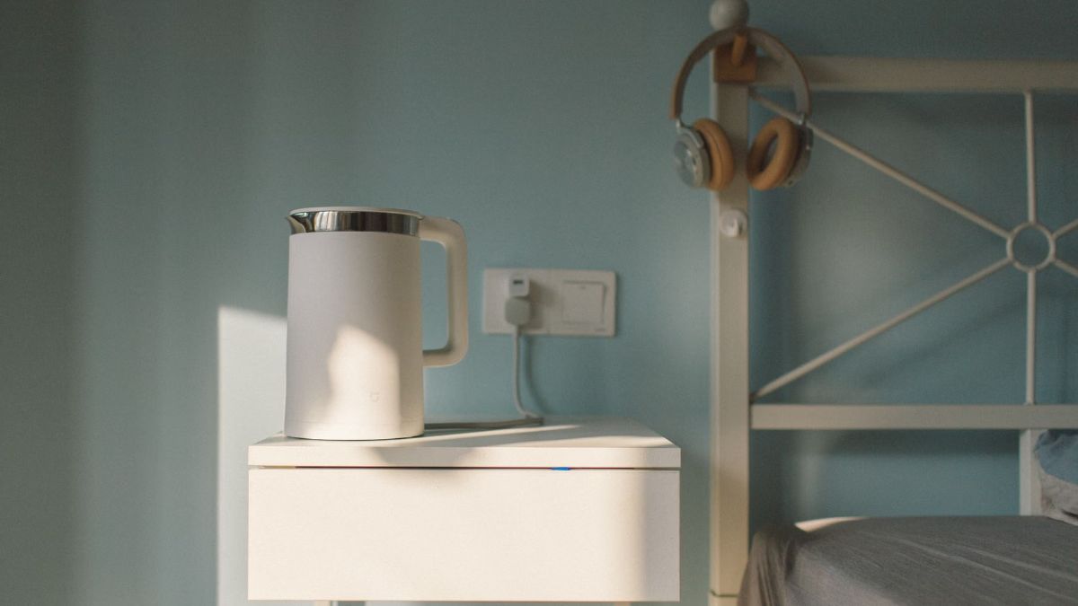 White electric kettle on a bedside table against a pale blue wall