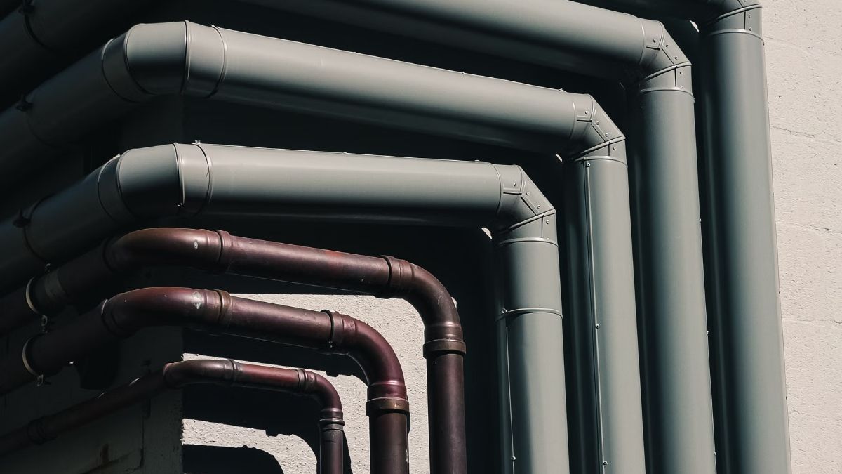 Close-up of several white-painted pipes bending in parallel